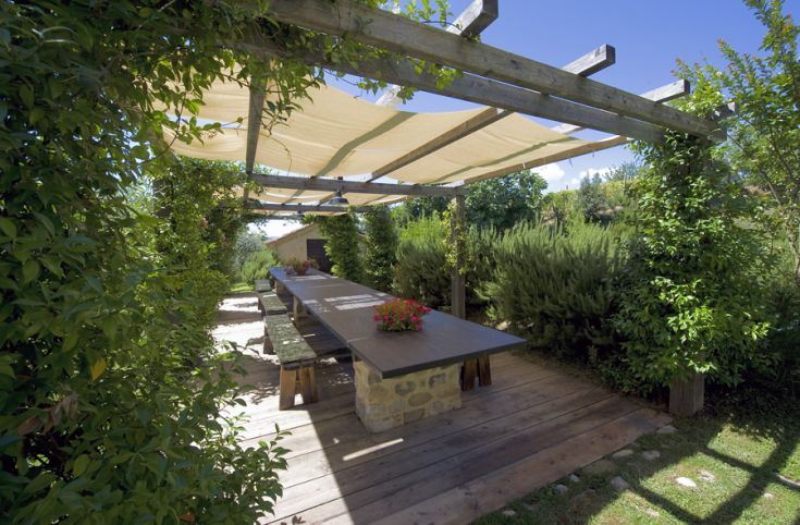 Ein Außenbereich mit einem großen Holztisch, umgeben von grünen Pflanzen. Ein ruhiger Ort zum Entspannen.