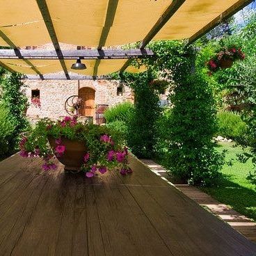 Ein Holztisch in einem Garten, umgeben von bunten Pflanzen und Blumen in einer gut gepflegten grünen Umgebung.