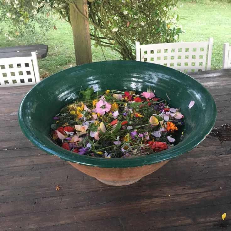 Eine grüne Schüssel mit bunten Blumen, die auf der Wasseroberfläche schwimmen.