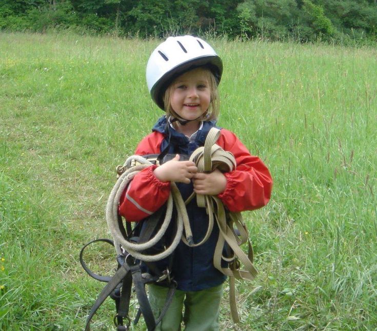 Glückliches Mädchen mit Helm und Seilen, bereit, die Natur in den umbrischen Parks zu erkunden.