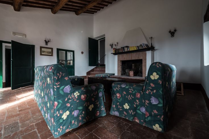 Soggiorno semplice e luminoso con divani a motivi floreali e un camino, dal design rustico.