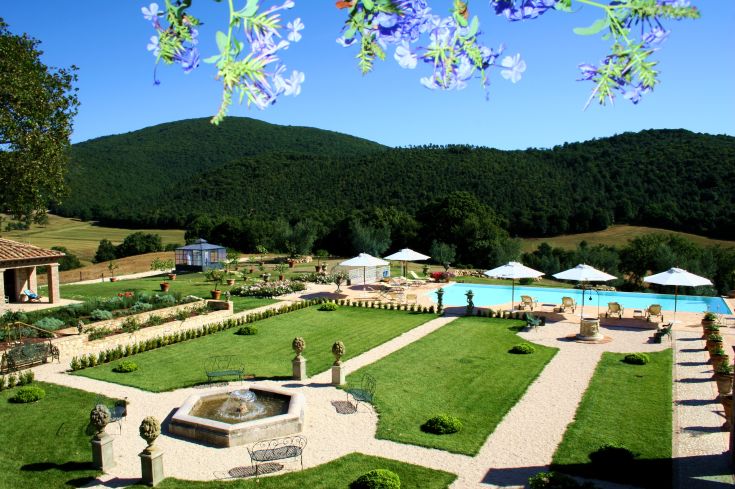 A estate with well-maintained gardens and a pool, located in the Umbrian countryside.