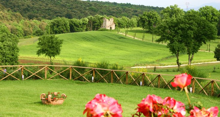 A panoramic view of lush hills with historic ruins in the distance.