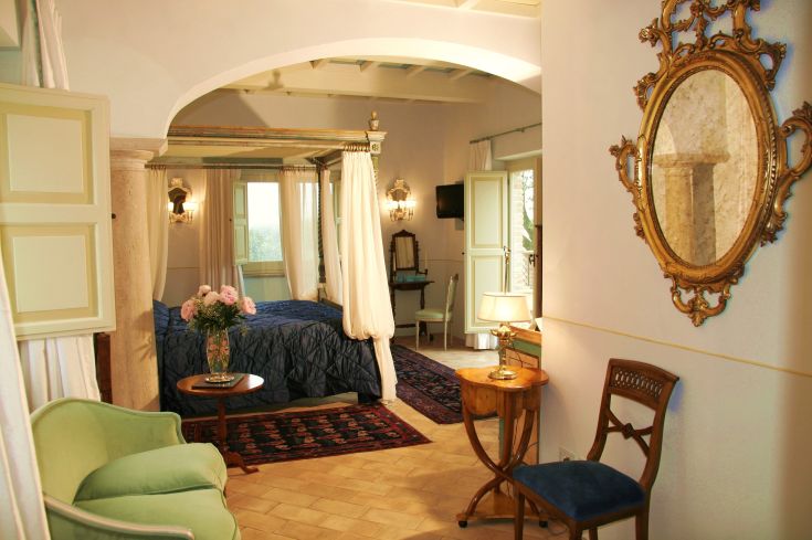 Cozy room with simple furnishings, canopied beds, and views of a natural landscape. Intimate and inviting atmosphere.