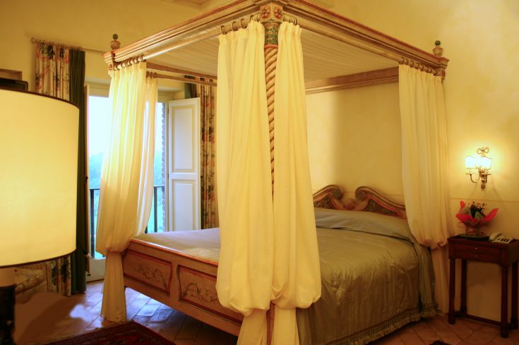 Simple bedroom with a four-poster bed and well-maintained furniture in a relaxing setting.
