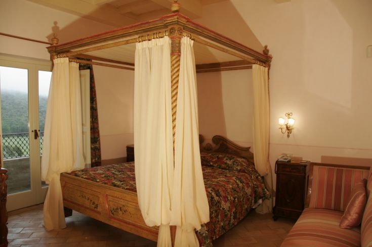 Bedroom with a canopy bed, simple decor and a view of a natural environment.