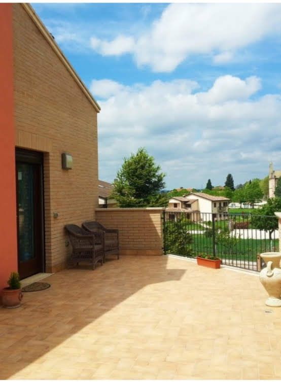 Une terrasse ensoleillée avec des chaises donnant sur un paysage de maisons et d'espaces verts environnants.