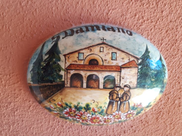 Une fresque représentant un bâtiment historique avec deux moines et des fleurs en arrière-plan.