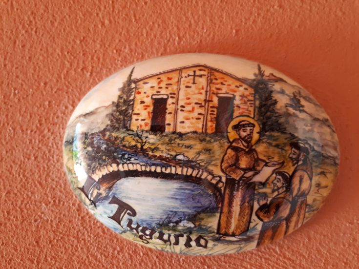 Une céramique décorative présentant un paysage avec un pont et des personnages religieux.