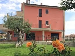 Une maison rose entourée d'un jardin vert avec des fleurs orange.