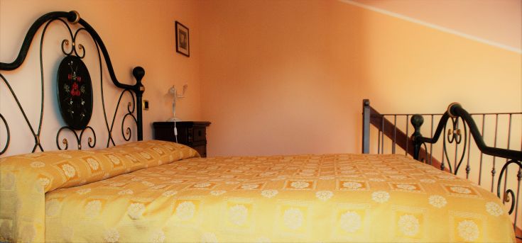 Spazio intimo e accogliente con un letto a baldacchino in ferro e semplici decorazioni.