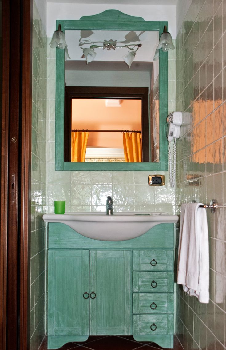 Bagno semplice in tonalità verdi, con lavabo moderno e specchio. Elementi decorativi sobrii.