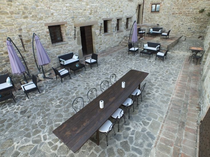 Outdoor area featuring a long table and chairs, set in a simple and natural environment.