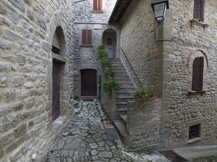 A stone road alongside stone buildings, featuring a staircase adorned with flowers.