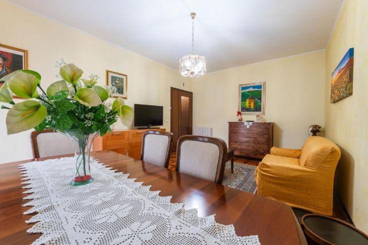 A warm and cozy living room featuring a table adorned with fresh flowers and artwork on the walls.