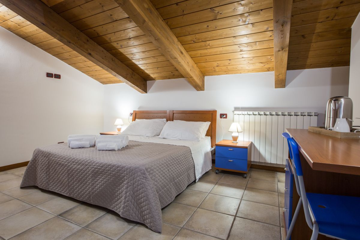 Cozy room with wooden ceiling, comfortable beds, and a study area.