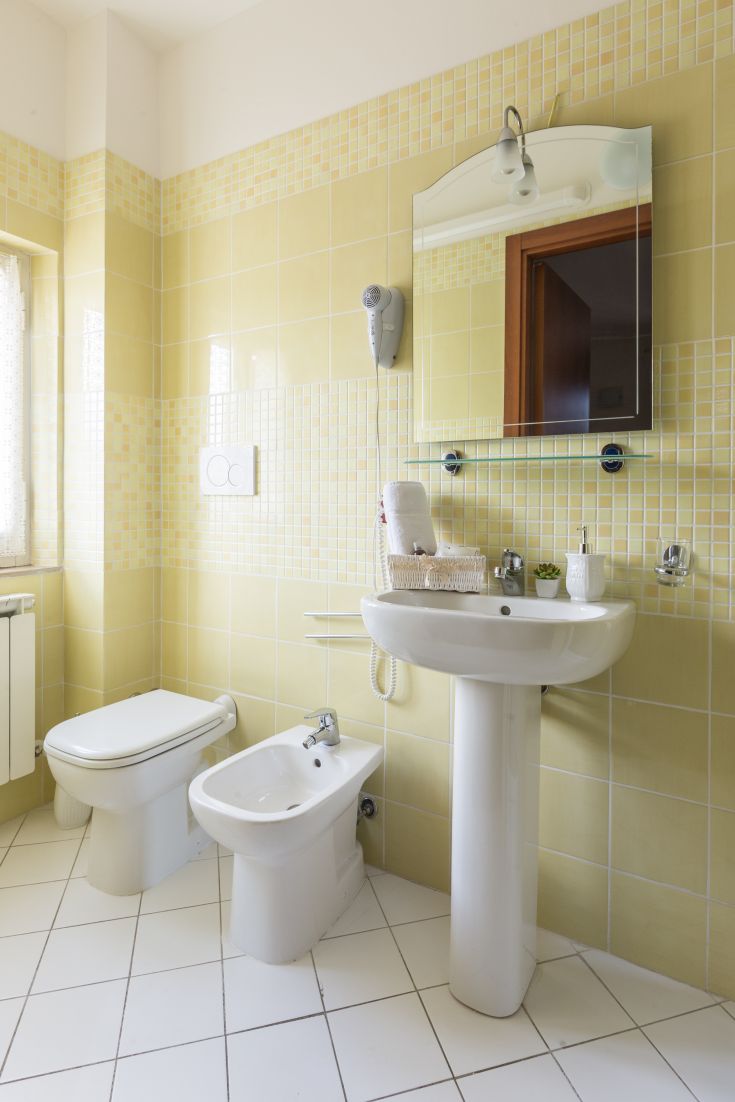 Bagno semplice con piastrelle gialle e dettagli minimalisti. Ambiante luminoso e gradevole.
