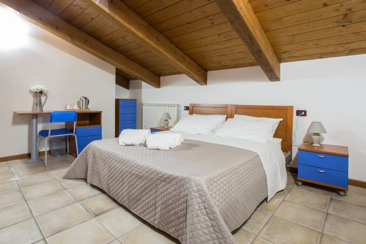 Camera semplice con letto matrimoniale e arredamento sobrio, affacciata su un giardino. Ideale per un soggiorno in Umbria.