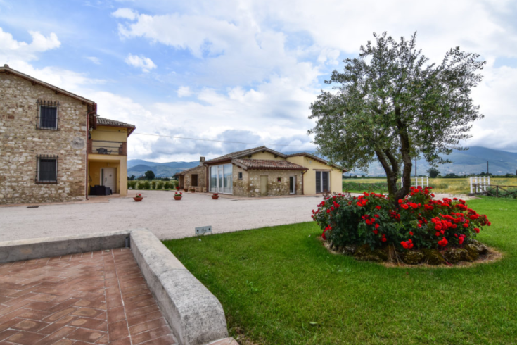 A peaceful agriturismo set in the Umbrian countryside, surrounded by lush greenery and natural features.