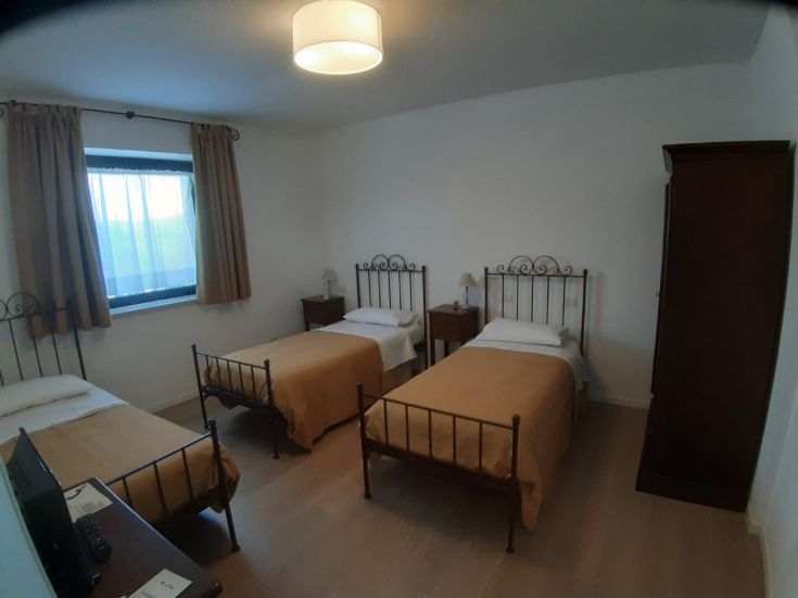 Camera semplice in agriturismo, con letti singoli e una finestra che offre luce naturale.