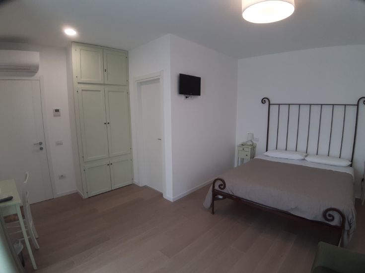 Accogliente camera di un agriturismo caratterizzata da un letto matrimoniale e un armadio verde.