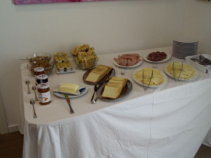 Colazione assortita con pane fresco, burro, salumi e marmellata di frutta.