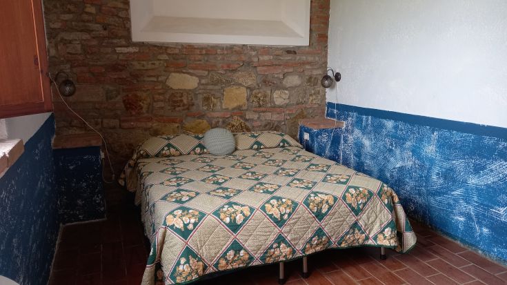 Elegant room with a double bed, stone and brick walls, perfect for a peaceful stay.