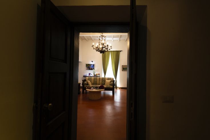 Interno di un'abitazione con un divano, lampadario e tende di colore verde.