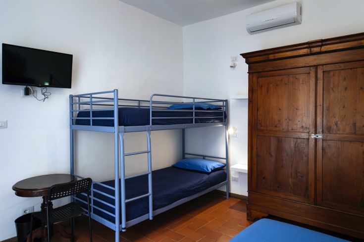 Camera con letto a castello in legno, dotata di TV e armadio. Un ambiente pratico e confortevole.