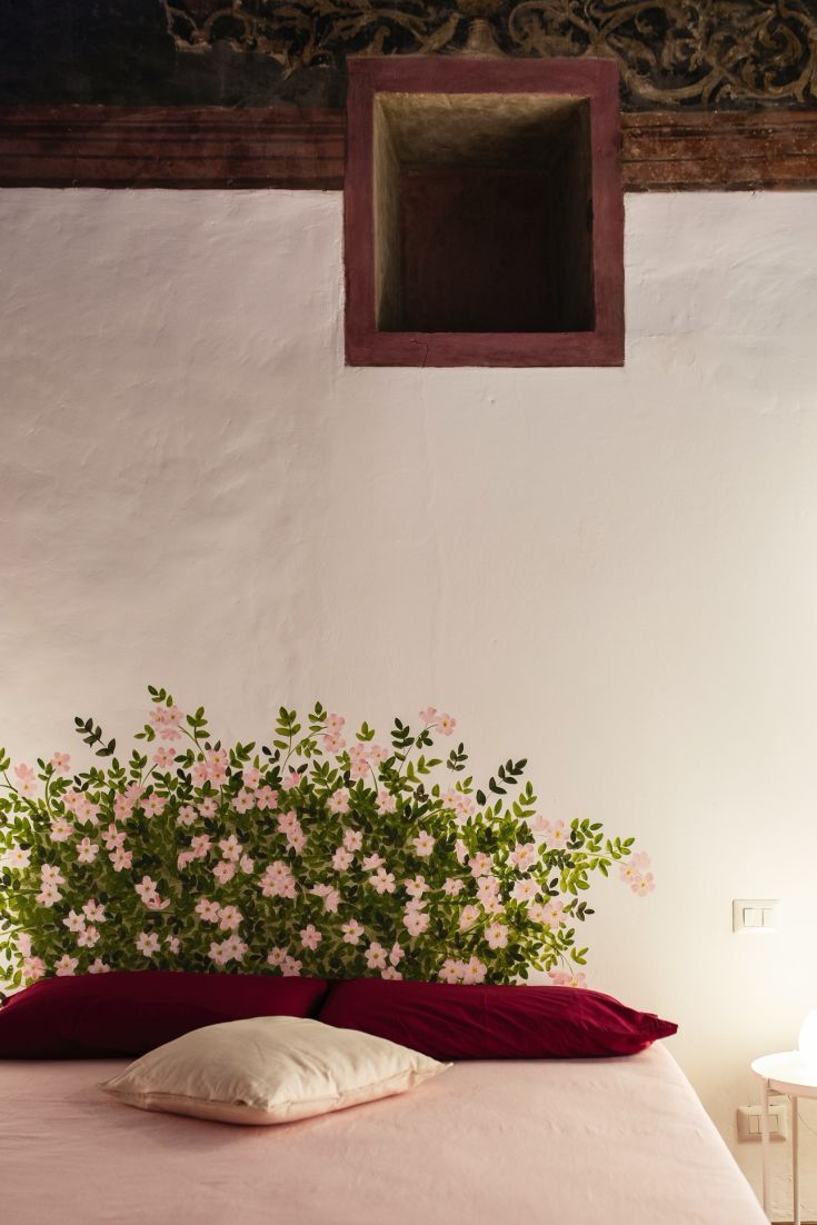 Camera accogliente con pareti decorate da motivi floreali e letti dotati di cuscini dai colori vivaci.