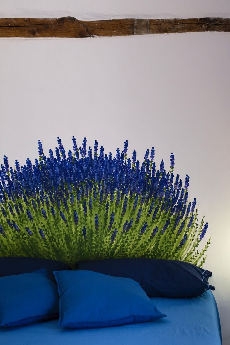 Una camera semplice con testata decorativa a forma di lavanda blu e cuscini di colore azzurro.