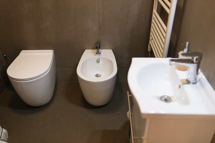 Interno sobrio di un bagno moderno con sanitari bianchi e dettagli semplici.
