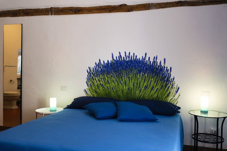 Una camera con letto blu e parete decorata a fiori, illuminata da luci morbide.