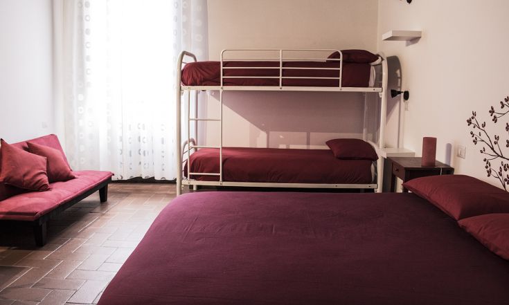 Camera semplice con letti a castello e matrimoniale, ben illuminata e dal design intimo.