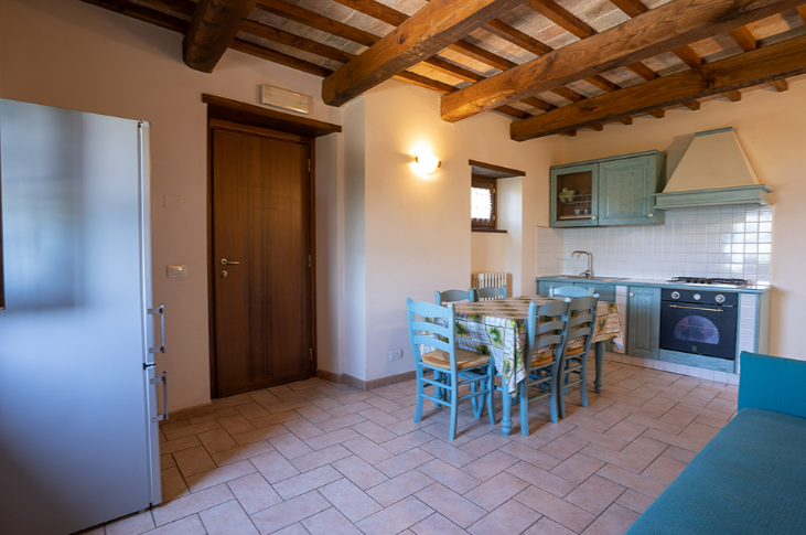 A cozy living room with an open kitchen, furnished with light wood furniture, ideal for relaxing moments.