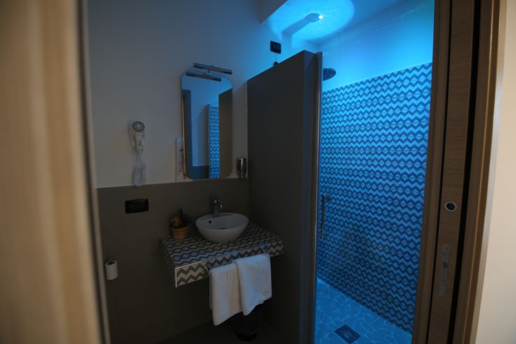 A contemporary bathroom featuring a shower, simple decorations, and soft blue lighting.