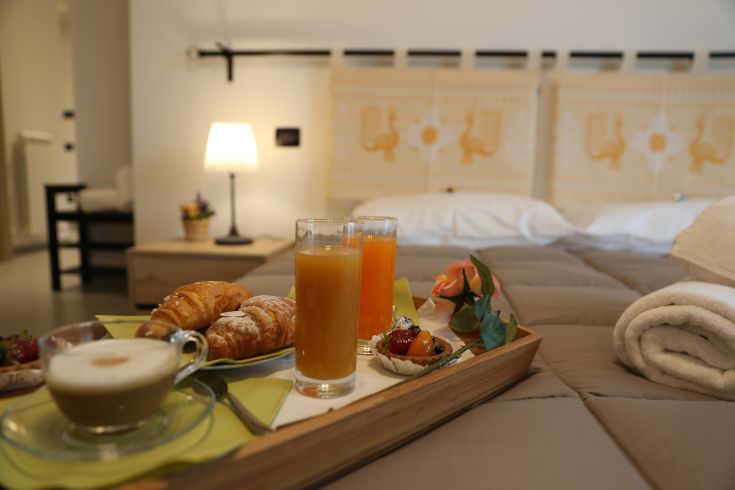 Breakfast in the room with croissants, drinks, and fruit on a tray. The setting is simple and cozy.