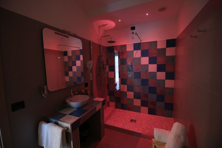 Minimalist bathroom design with vibrant tiles, a mirror, and soft lighting.