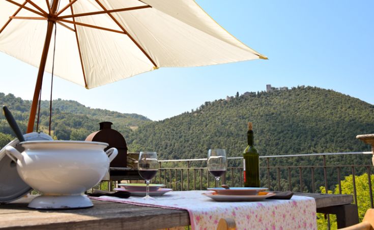 Tisch im Freien gedeckt für eine Mahlzeit, umgeben von grünen Hügeln.