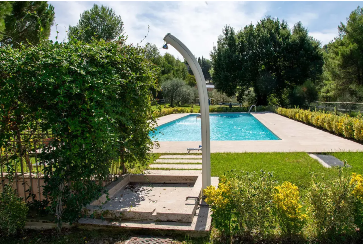 Pool in a rural guesthouse, surrounded by greenery, plants, and relaxation areas.