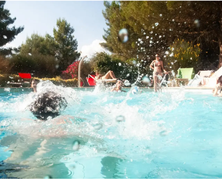 Ein Sommertag am Pool, mit Menschen, die sich im Wasser unter der Sonne vergnügen und spielen.