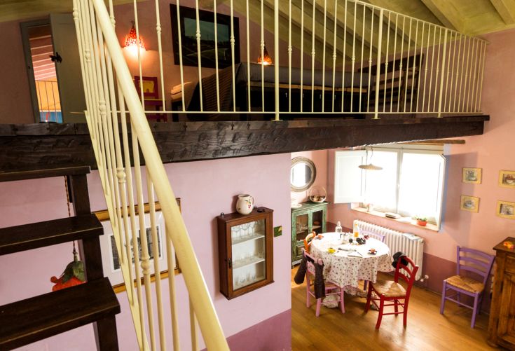 Einfaches Interieur einer Wohnung mit Essbereich und möbliertem Dachboden.