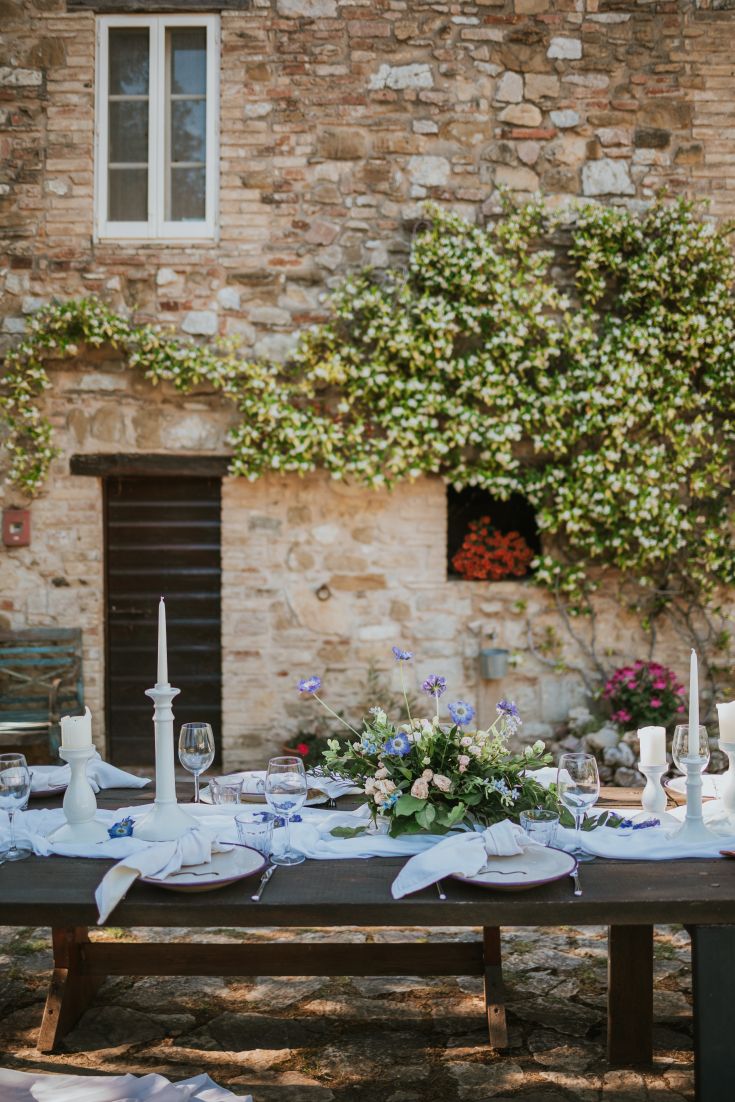 Ein einfach gedeckter Tisch im Freien, umgeben von Grün in der Nähe eines Ferienhauses.