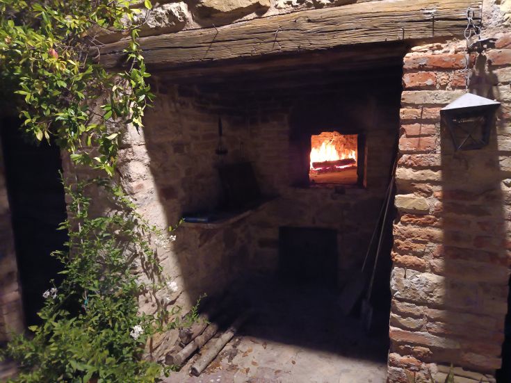 Ein beleuchteter Weg in einer Ecke eines alten rustikalen Gebäudes, umgeben von einigen grünen Pflanzen.