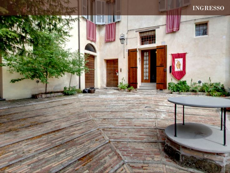 Ingresso con pavimento in mattoni e dettagli storici, che riflette il contesto architettonico locale.