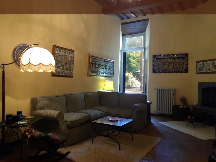 Un soggiorno semplice e accogliente con un divano confortevole e luce naturale, arredato con elementi decorativi.