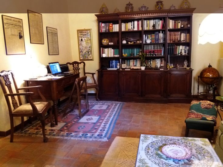 Una stanza semplice e accogliente con libreria e scrivania in legno, decorata con qualche elemento storico.