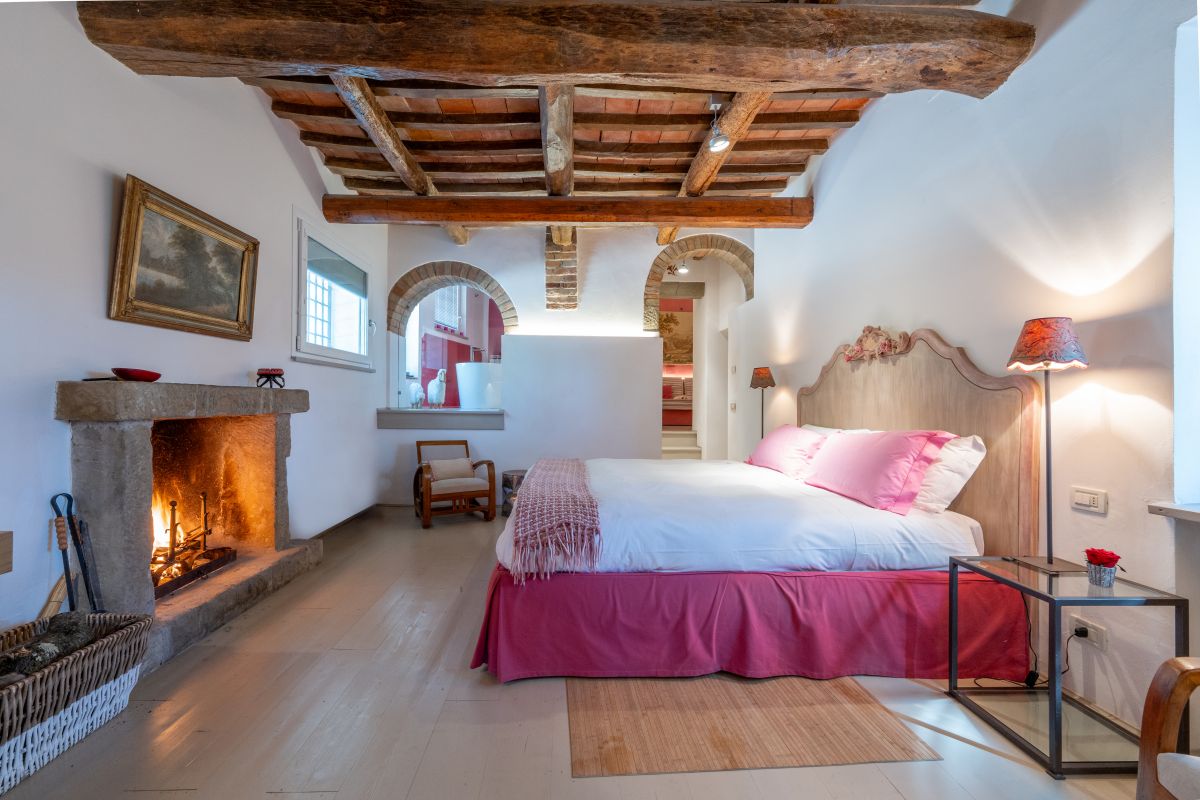 Camera semplice con camino, letti matrimoniali e decorazioni sobrie in un'atmosfera tranquilla.