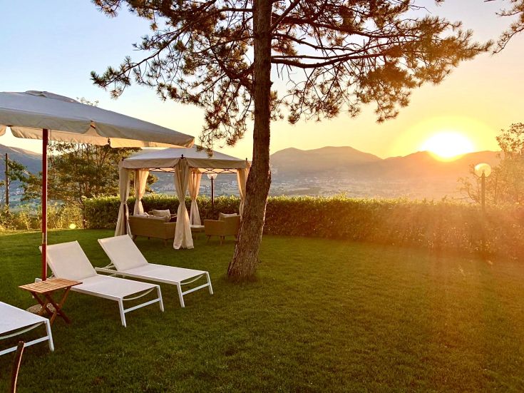 Un'area rilassante con lettini e un gazebo, che si affaccia su un panorama suggestivo al tramonto.