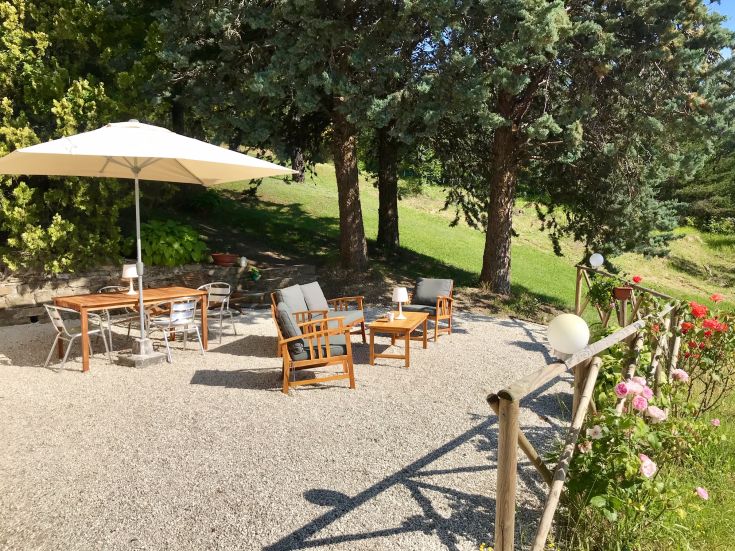 Area all'aperto con un tavolo e sedie, immersa nel verde e adatta per momenti di relax.